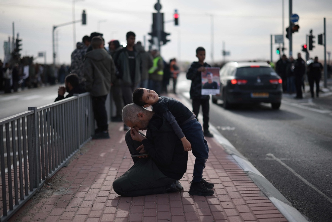 A child leans on an adult as members of the Bedouin community protests at the road junction outside the village of Bir Hadaj near the Israeli Revivim kibbutz in the Negev desert. (AFP)