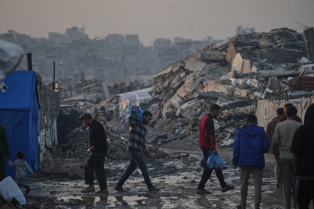 Palestinians walk past a tent camp amid buildings destroyed by Israeli air and ground operations in Gaza City, Tuesday, Jan. 6, 2026. (AP Photo)