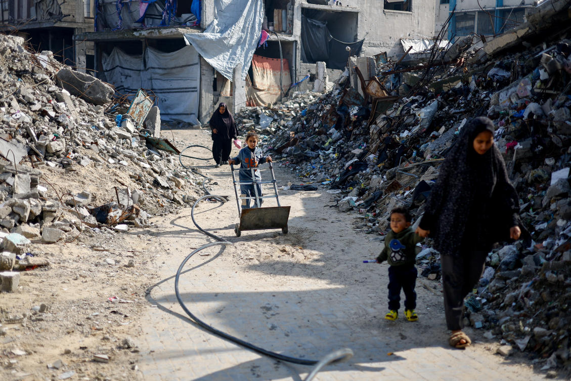 Palestinians walk past the rubble of residential buildings destroyed during the war, in Jabalia, northern Gaza Strip, Wednesday. (Reuters)