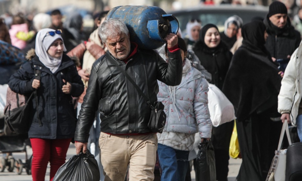 Residents carry their belongings as they flee the Ashrafieh Kurdish neighbourhood of Aleppo, Jan. 7, 2026. (AFP)