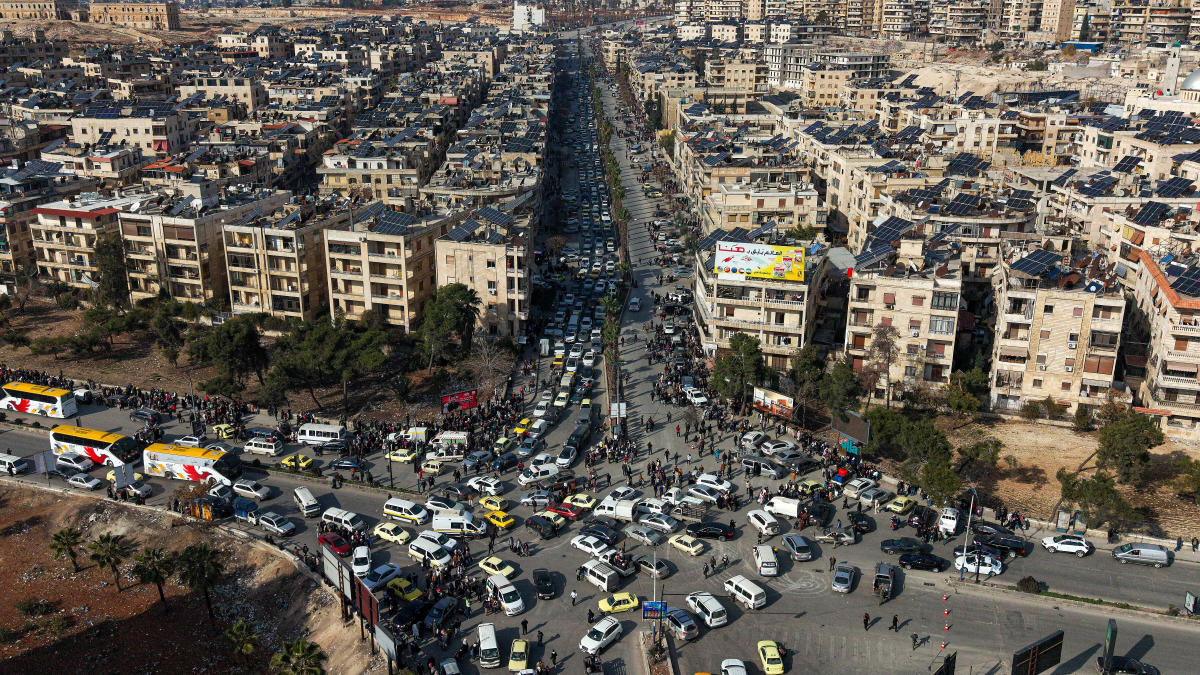 An aerial view shows Syrian residents in vehicles, queueing to flee from Sheikh Maqsoud and Achrafieh neighborhoods after clashes broke out on Tuesday between Syrian government forces and Kurdish fighters in a contested area of the northern city of Aleppo, Syria, Wednesday, Jan. 7, 2026. (AP)