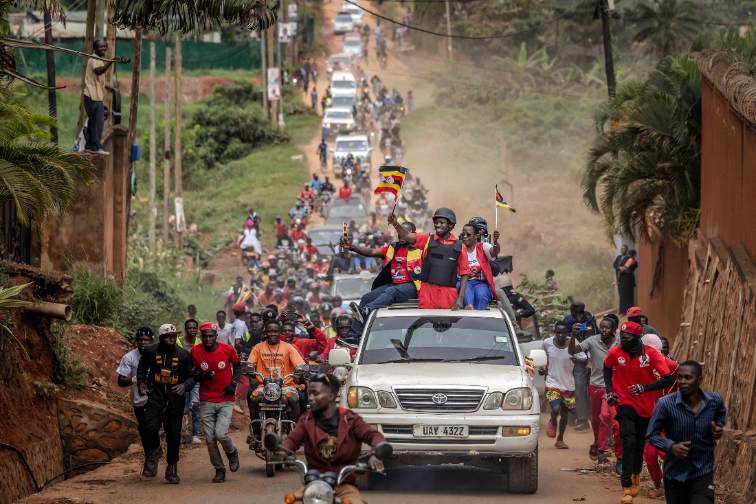 Opposition leader and presidential candidate for the National Unity Platform Robert Kyagulanyi Ssentamu, popularly known as Bobi Wine, waves a Ugandan flag atop a car as he is followed by a crowd of supporters on his way to a campaign rally in Kampala. (AFP)
