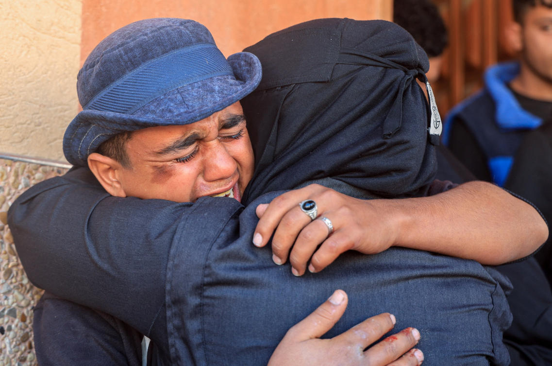 Mourners hug each other during the funeral of Palestinians who were killed in an Israeli strike on Sunday, at Nasser Hospital in Khan Younis, southern Gaza Strip, January 11, 2026. (Reuters)