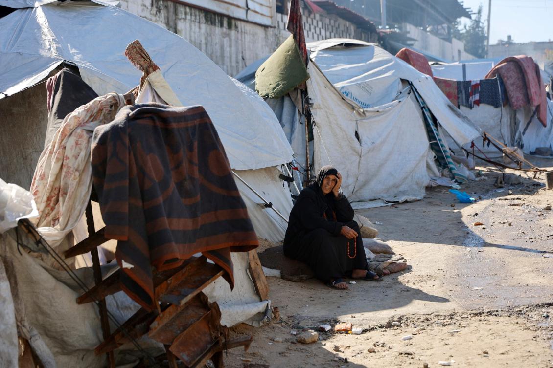 A displaced Palestinian woman rolls her pray beads as she sits outside a family tent shelter set-up in Gaza City on January 11, 2026. (AFP)