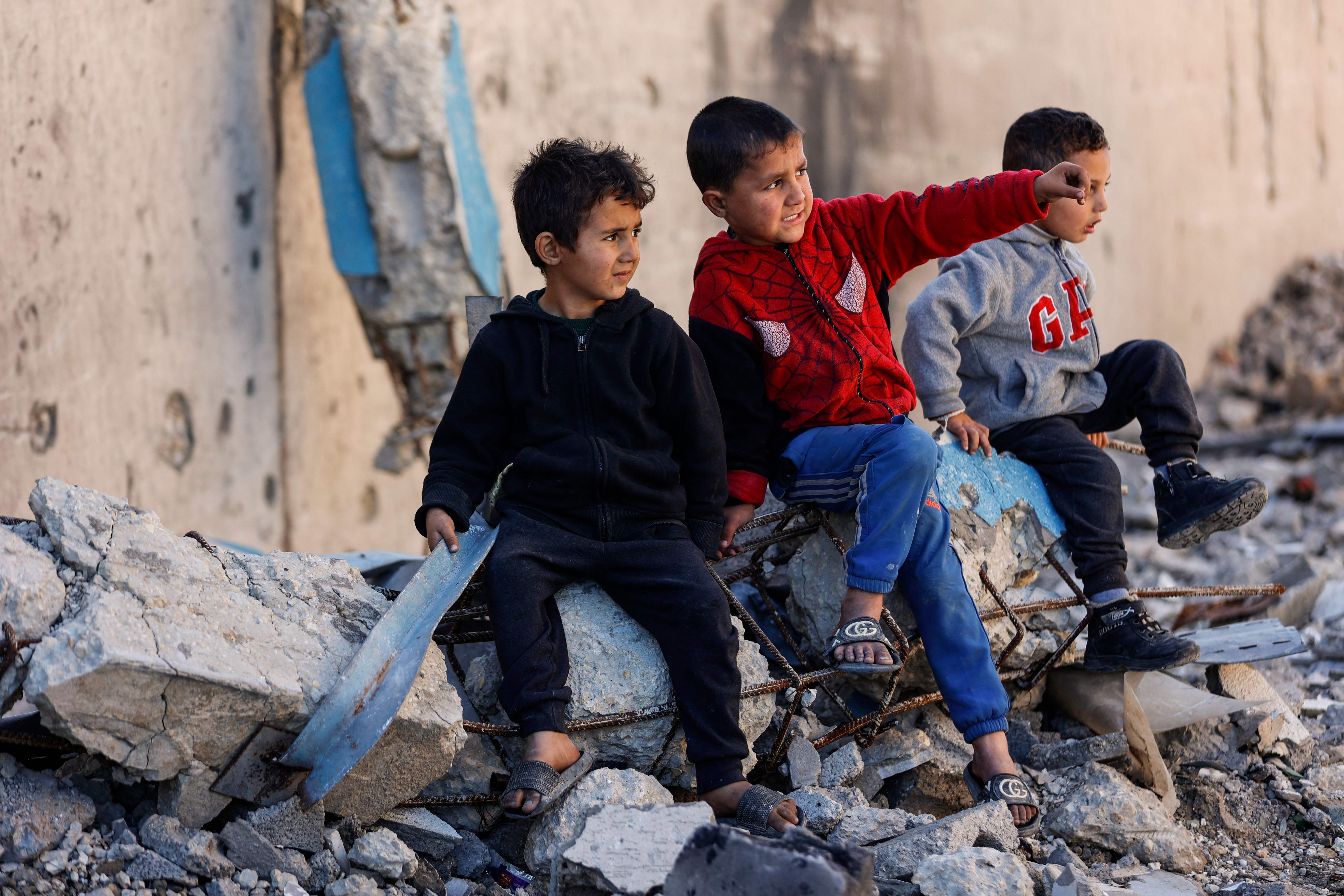 Displaced Palestinian children living in the vicinity of The United Nations Relief and Works Agency for Palestine Refugees in the Near East's (UNRWA) headquarters sit on rubble from a destroyed building, in Gaza City on January 11, 2026. (AFP)