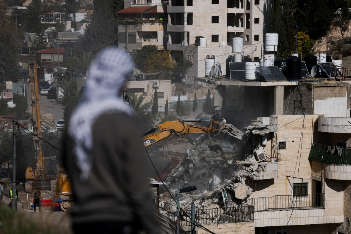A man watches as Israeli forces demolish a residential building where Palestinian families lived, near the Silwan neighbourhood of East Jerusalem, December 22, 2025. (Reuters)