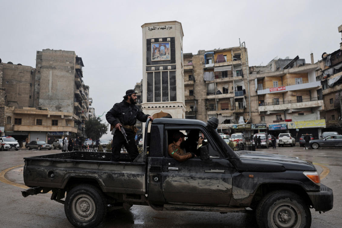 A member of the Syrian army stands on a pick-up truck in the Ashrafieh neighbourhood, after the Kurdish-led Syrian Democratic Forces (SDF) fighters left the Syrian city of Aleppo on Sunday, state-run Ekhbariya TV said, following a ceasefire deal that allowed evacuations after days of deadly clashes, in Aleppo, Syria, January 11, 2026. REUTERS/Khalil Ashawi