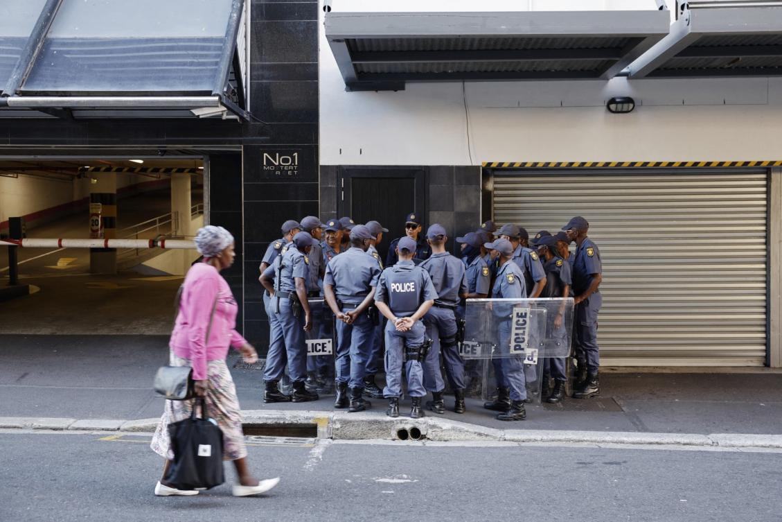 A pedestrian walks past South African Police Service (SAPS) officers gathering ahead of the 2023 state-of-the-nation address (SONA) at the Cape Town City Hall in Cape Town on February 9, 2023. (AFP)