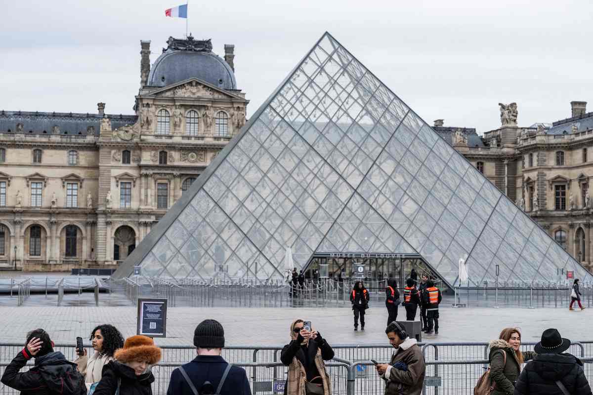 Tourists stand behind barriers blocking the access to the Louvre main courtyard. (AFP/File)