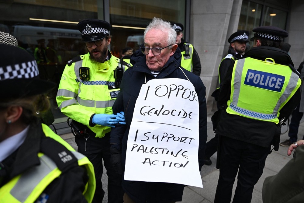 A protester is escorted away by police officers for taking part in a demonstration in support of "Defend Our Juries" and their campaign against the ban on Palestine Action, outside Britain's Ministry of Justice in London on November 20, 2025. (AFP/File)