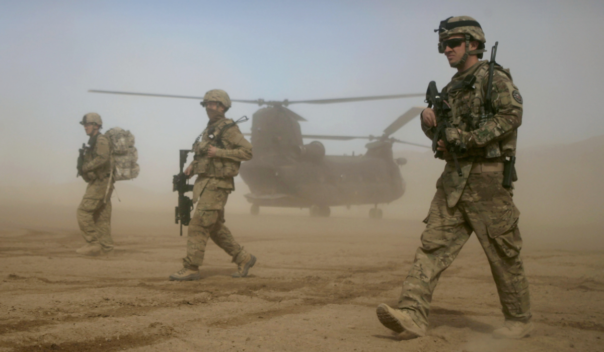 US soldiers, part of the NATO-led International Security Assistance Force (ISAF), walk as a US Chinook helicopter is seen on the back ground in Shindand, Herat, west of Kabul, Afghanistan, Jan. 28, 2012. (AP)