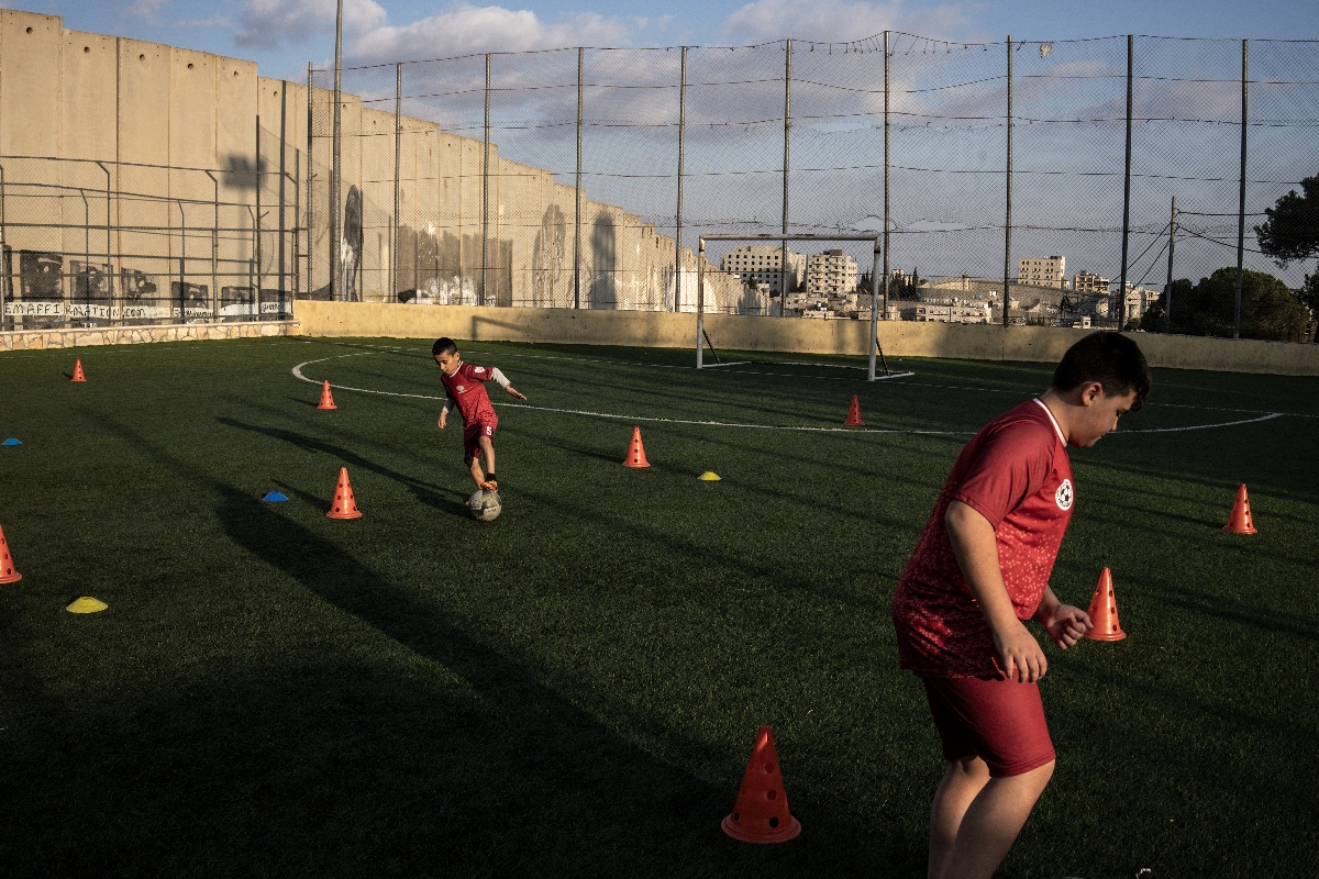 Displaced Palestinian youths take part in a training session at the Aida Refugee Camps football pitch, next to the separation wall outside Bethlehem in the occupied West Bank, on December 16, 2025, a few weeks after an Israeli military decision to demolish the field. (AFP)