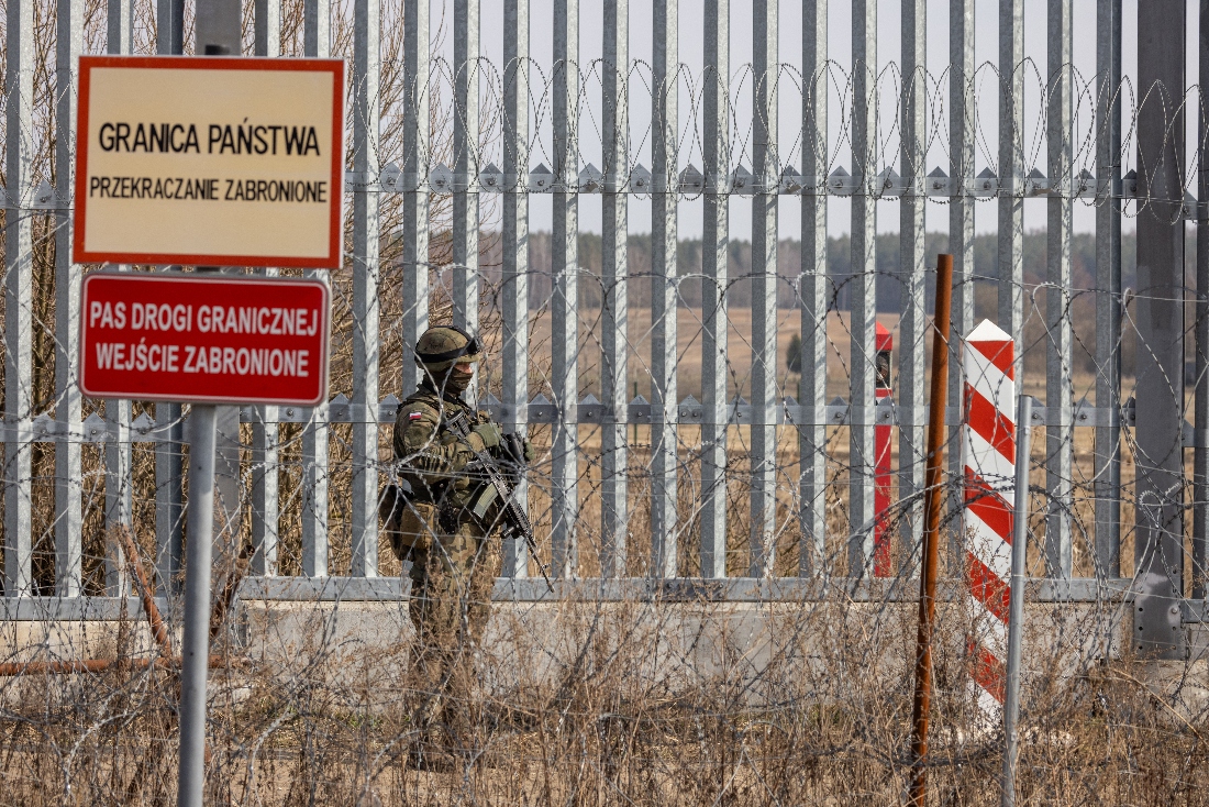 A Polish soldier stands next to the placard reading "Border State" at the Belarusian border in Ozierany Male, eastern Poland. (AFP)