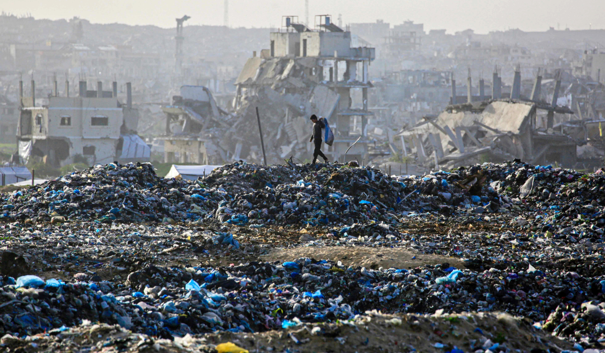 A Palestinian boy searches for recyclable material at a landfill against the backdrop of destroyed buildings in Khan Yunis, in the southern Gaza Strip on January 25, 2026. (AFP)