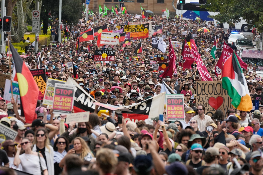 Flags and placards are carried by demonstrators during a "Invasion Day" rally and match on Australia Day in Sydney, Australia. (AP)