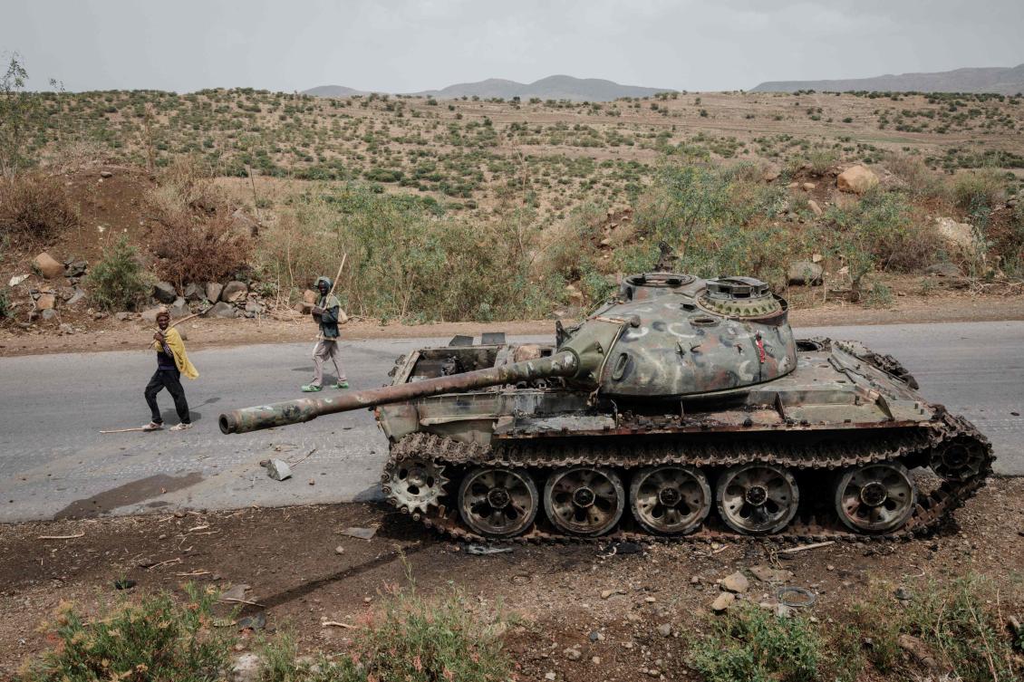 Local farmers walk next to a tank of alledged Eritrean army that is abandoned along the road in Dansa, southwest of Mekele in Tigray region, Ethiopia, on June 20, 2021. (File/AFP)
