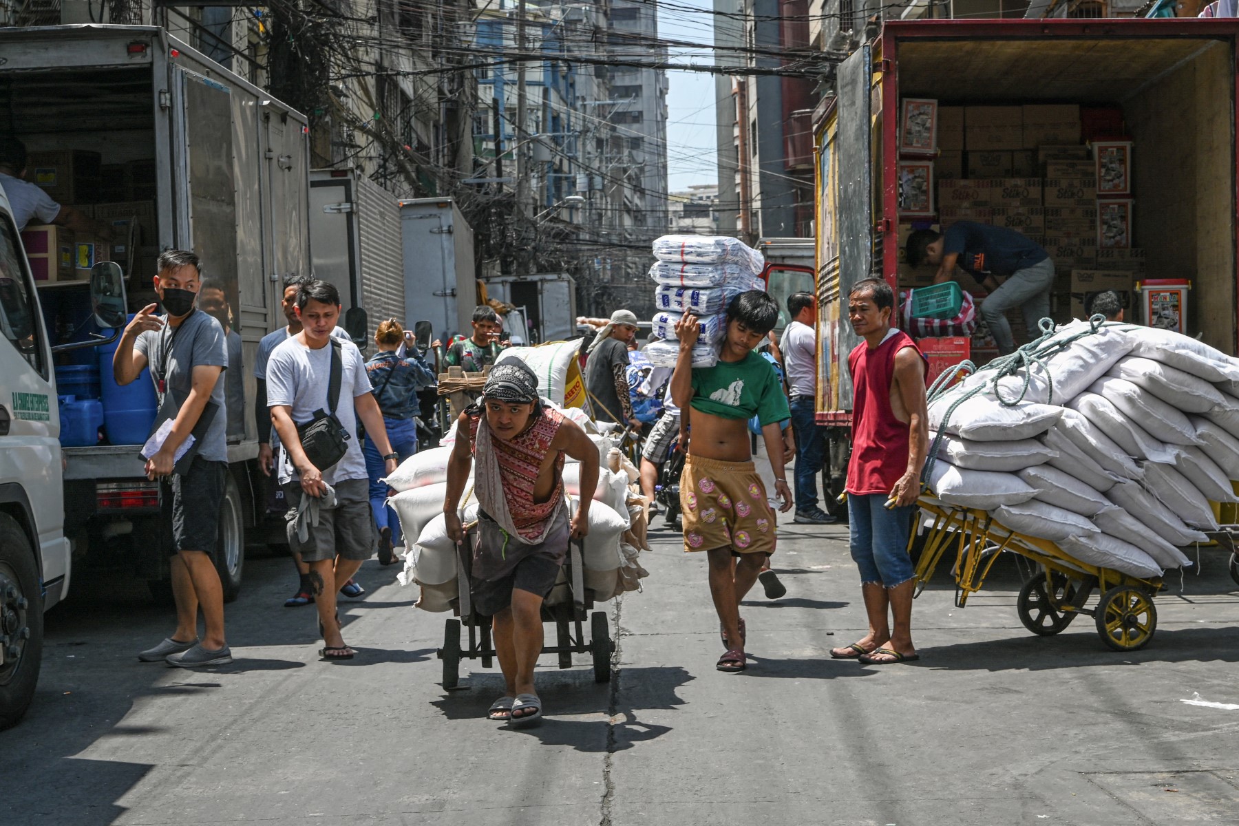 Men pull a trolley of agricultural products along a street in Manila on May 9, 2024. (AFP)