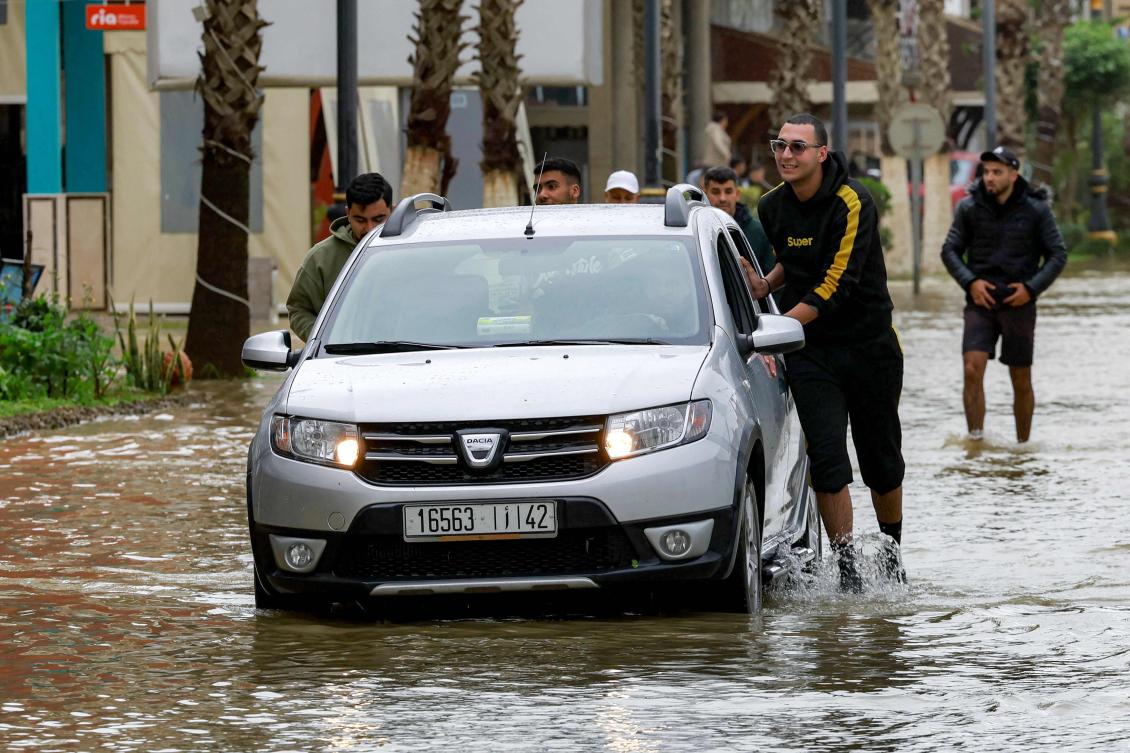Men push a vehicle moving along an inundated road in Morocco’s northwestern city of Ksar el-Kebir on Jan. 29, 2026, as several neighborhoods flooded in the city due to a rise in the water level of the Loukkos river following recent heavy rainfall. (AFP)