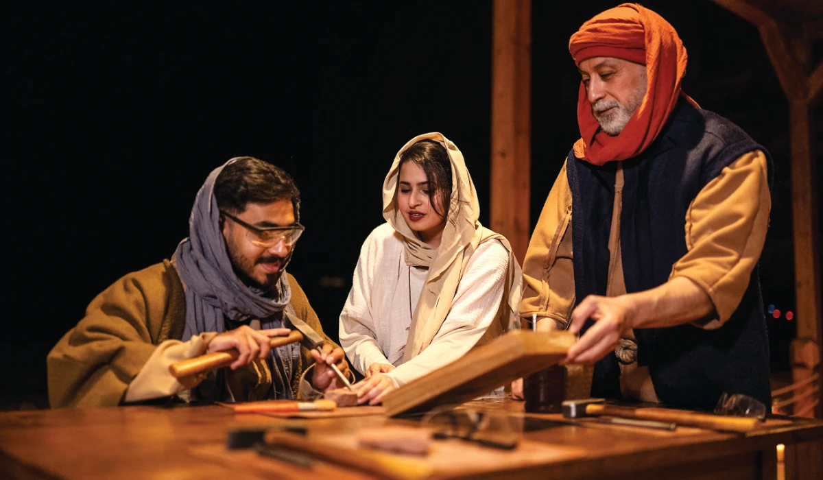 The team at ‘Ikmah After Dark: Secrets of the Scribe’ showing a visitor how to carve on a stone. (Supplied)