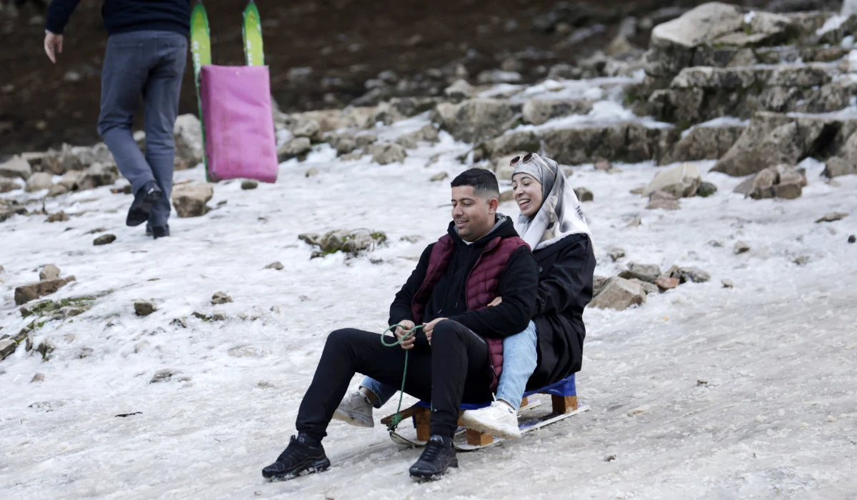 A man and a woman slide with a luge sled on thin snow at the Michlifen ski resort in the Atlas Mountains near the Moroccan city of Ifrane, where the lack of snow is hindering tourism, on January 11, 2025. (AFP)