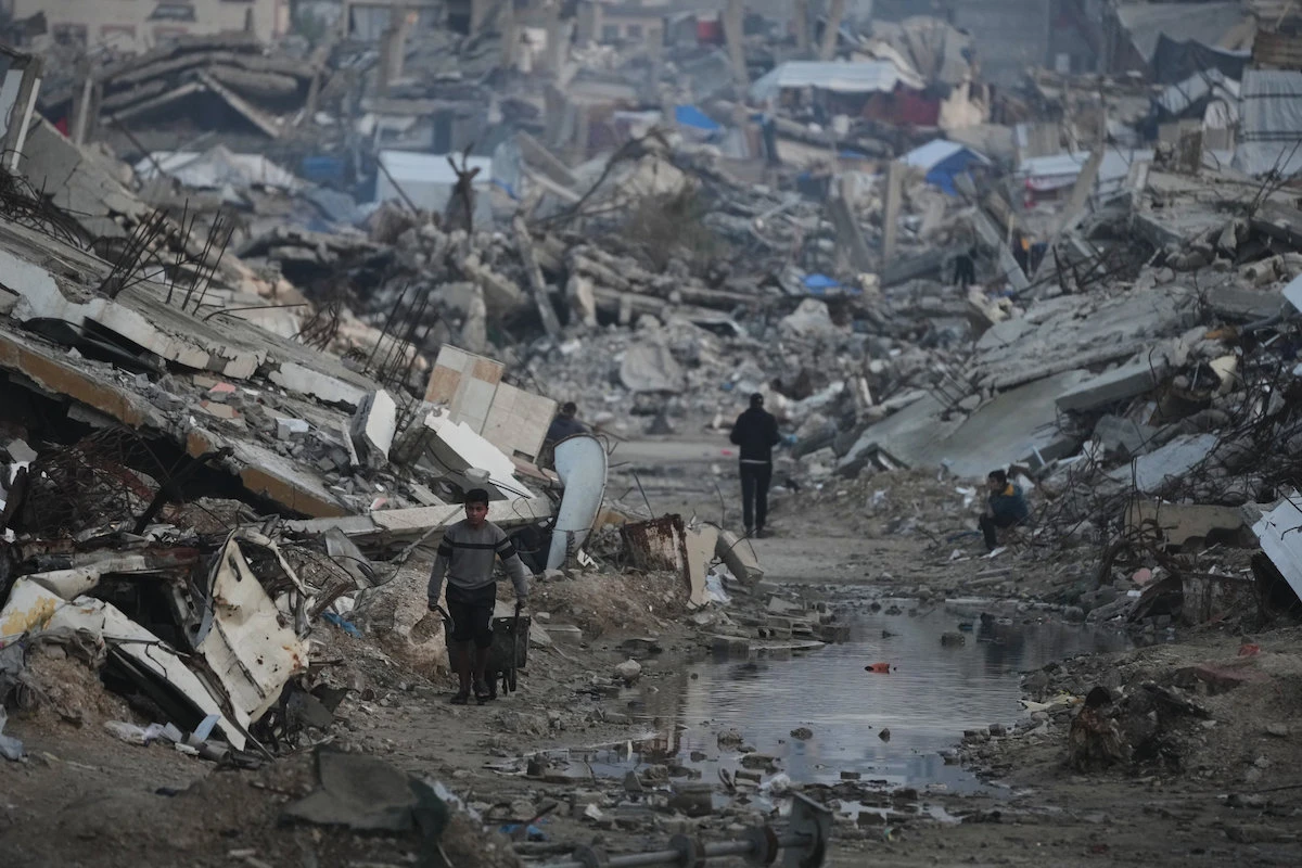 Palestinians walk amid buildings destroyed by Israeli air and ground operations in Gaza City. (AP)