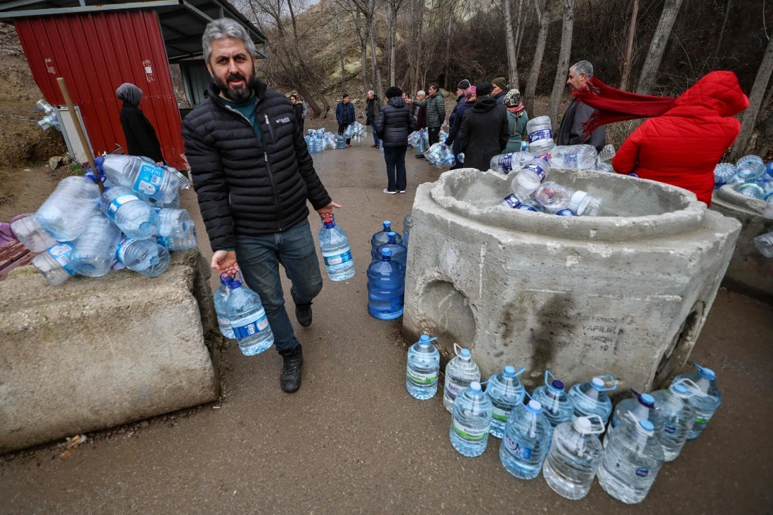 A man walks with empty containers to fetch water during water shortage in the Araplar neighborhood of the Mamaklar district in Ankara, Turkiye. (AFP)