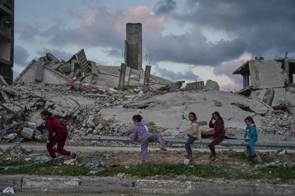 Palestinian girls play amid buildings destroyed by Israeli air and ground operations in the Zeitoun neighborhood of Gaza City, Wednesday, Jan. 14, 2026. (AP Photo)