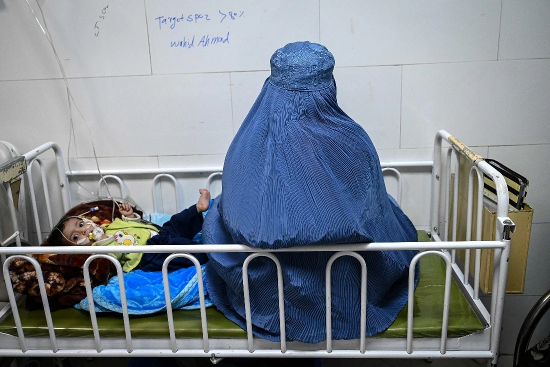 Afghan burqa-clad woman sitting next to her malnourished child inside the Medecins Sans Frontieres (MSF) therapeutic nutrition centre at a hospital in Herat, Afghanistan. (AFP)