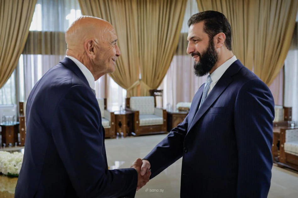 US special envoy to Syria Tom Barrack shakes hands with Syria's President Ahmad Al-Sharaa, in Damascus, Syria on Sunday. (SANA via AP)
