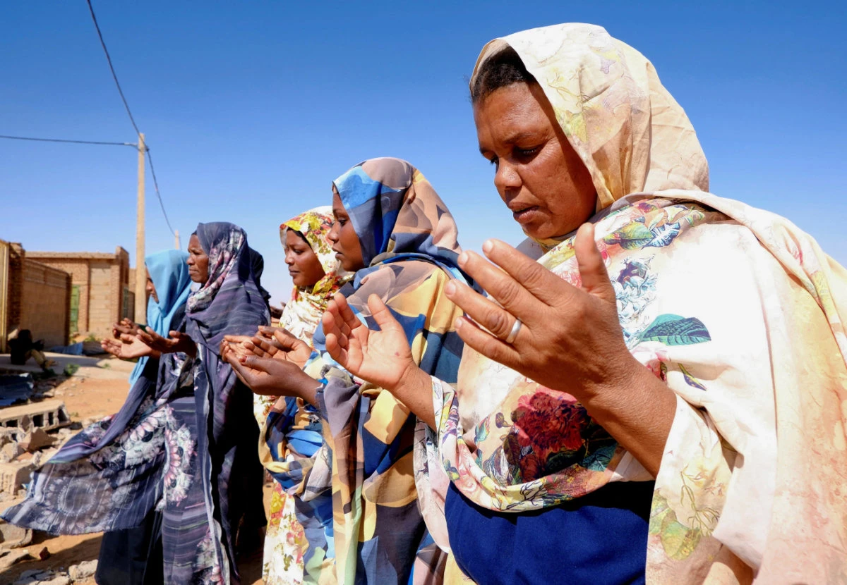 Women pray for mercy for the deceased in front of a house struck by a drone in Sudan. The conflict has claimed tens of thousands of lives. (Reuters)