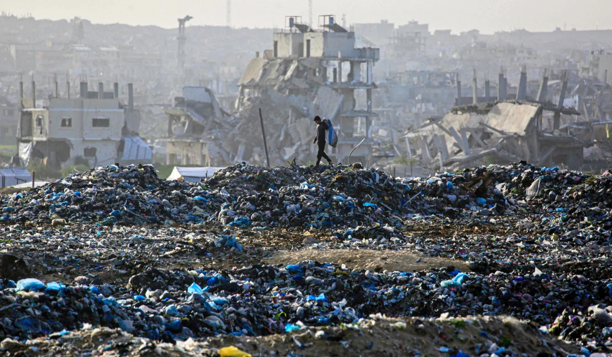 A Palestinian boy searches for recyclable material at a landfill against the backdrop of destroyed buildings in Khan Yunis, in the southern Gaza Strip on January 25, 2026. (AFP)