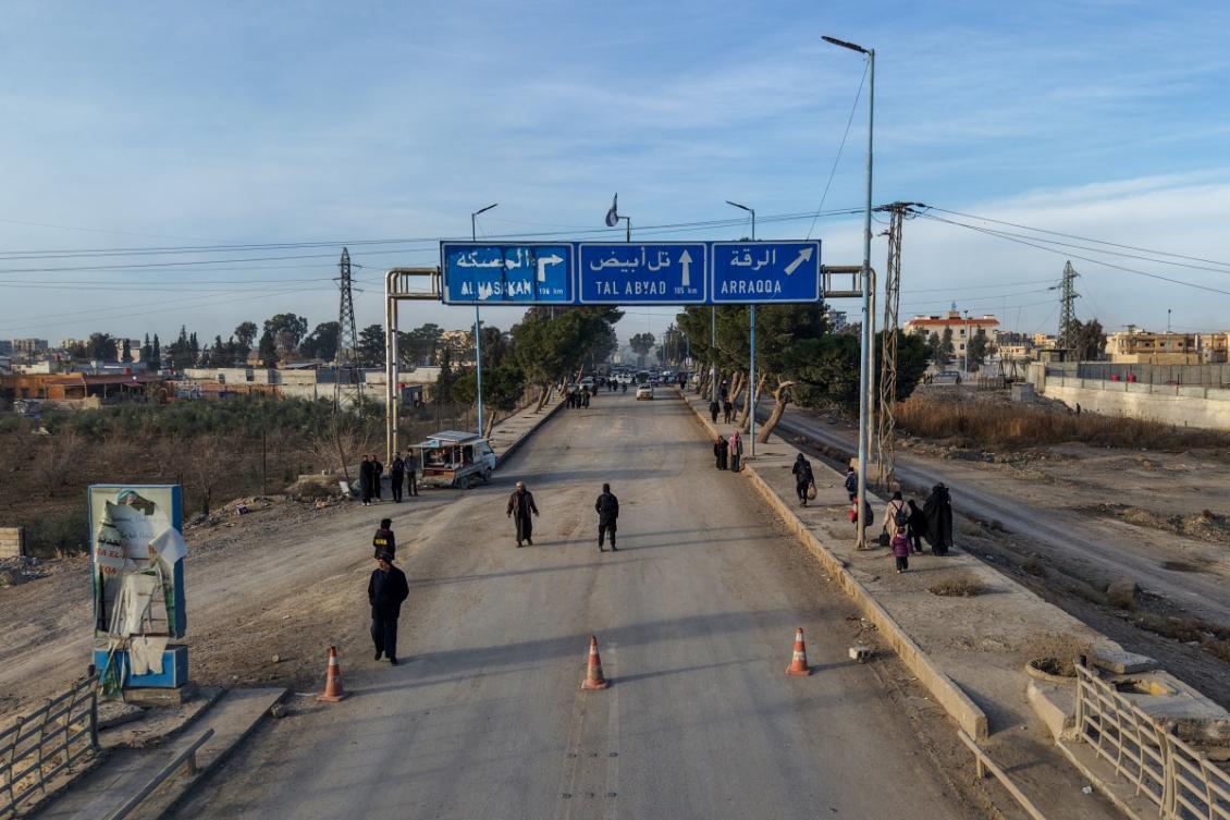 An aerial photograph shows people walking along a street at the entrance to the northeastern Syrian city of Raqa, once the Daesh group's de facto capital in Syria, on January 21, 2026. (AFP)