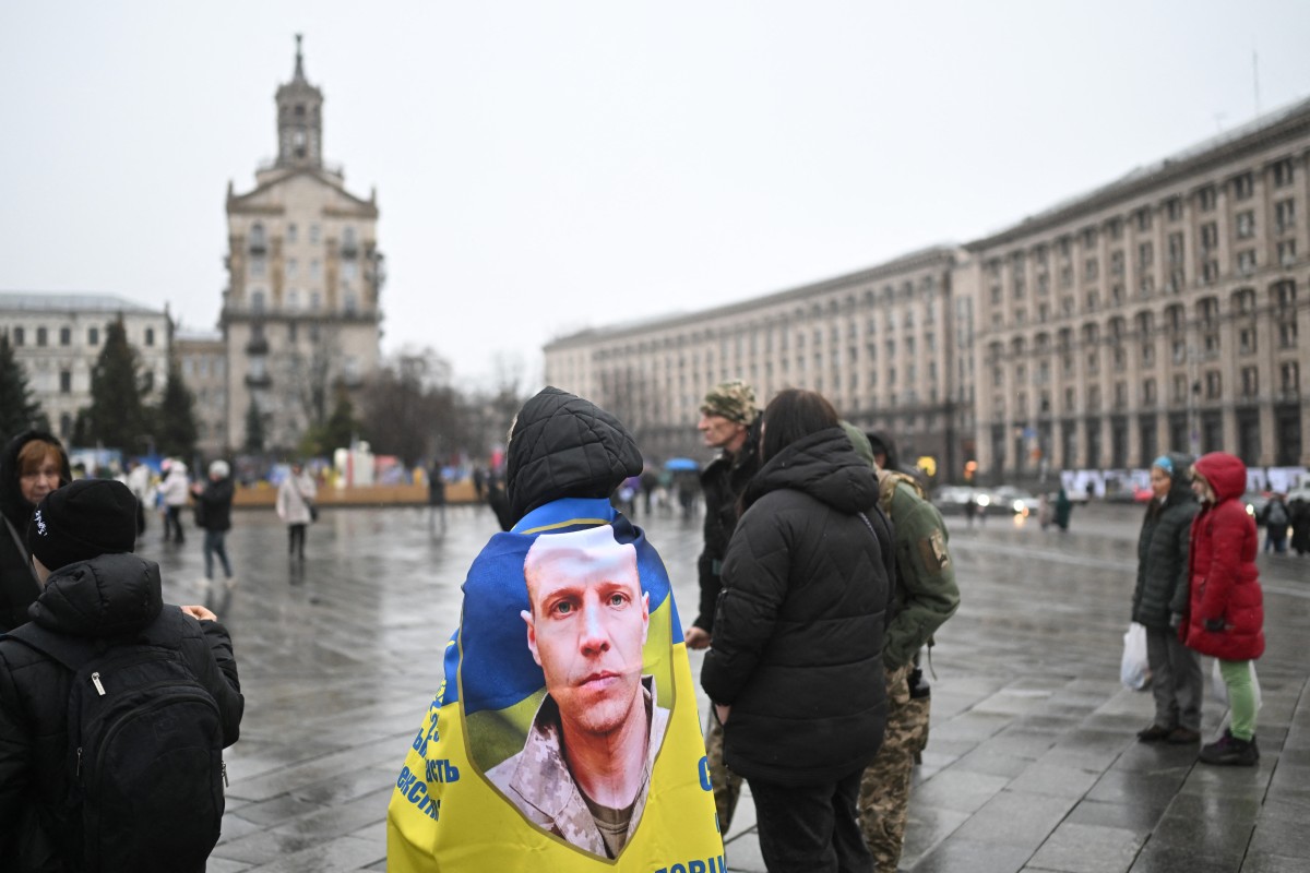 A demonstrator wrapped in a Ukrainian flag with a photo of a Ukrainian serviceman attends a rally in support of missing and captured soldiers, in Kyiv, Nov. 22, 2025. (AFP)