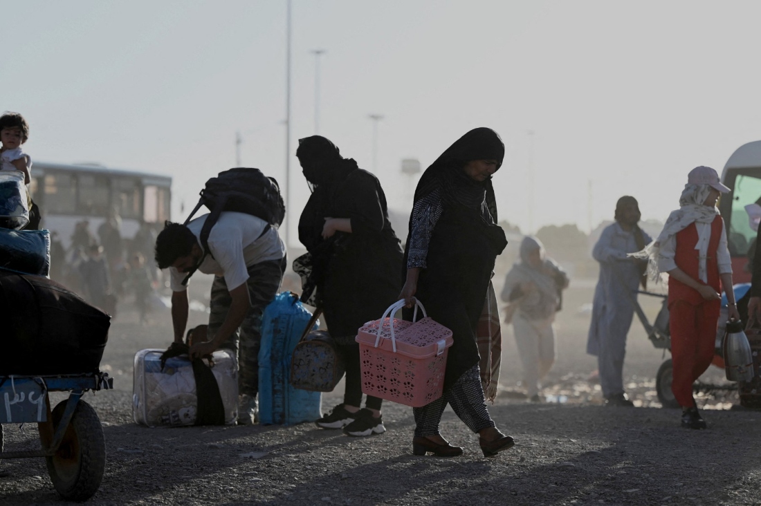 Afghan refugees carrying their belongings as they arrive at the zero point of the Islam Qala border crossing between Afghanistan and Iran. (AFP)