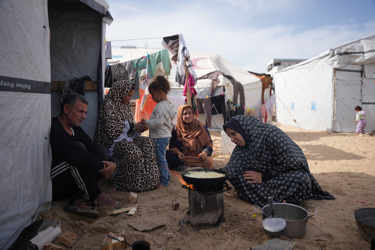 Palestinians cook food over a fire beside their tent in Khan Younis, in the southern Gaza Strip on Saturday. (AP)