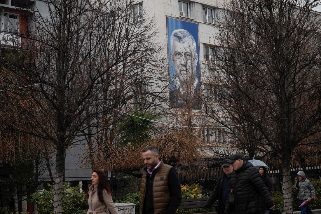 Pedestrians walk past a giant banner depicting former Kosovo president Hashim Thaci in Pristina, Kosovo. (AFP)