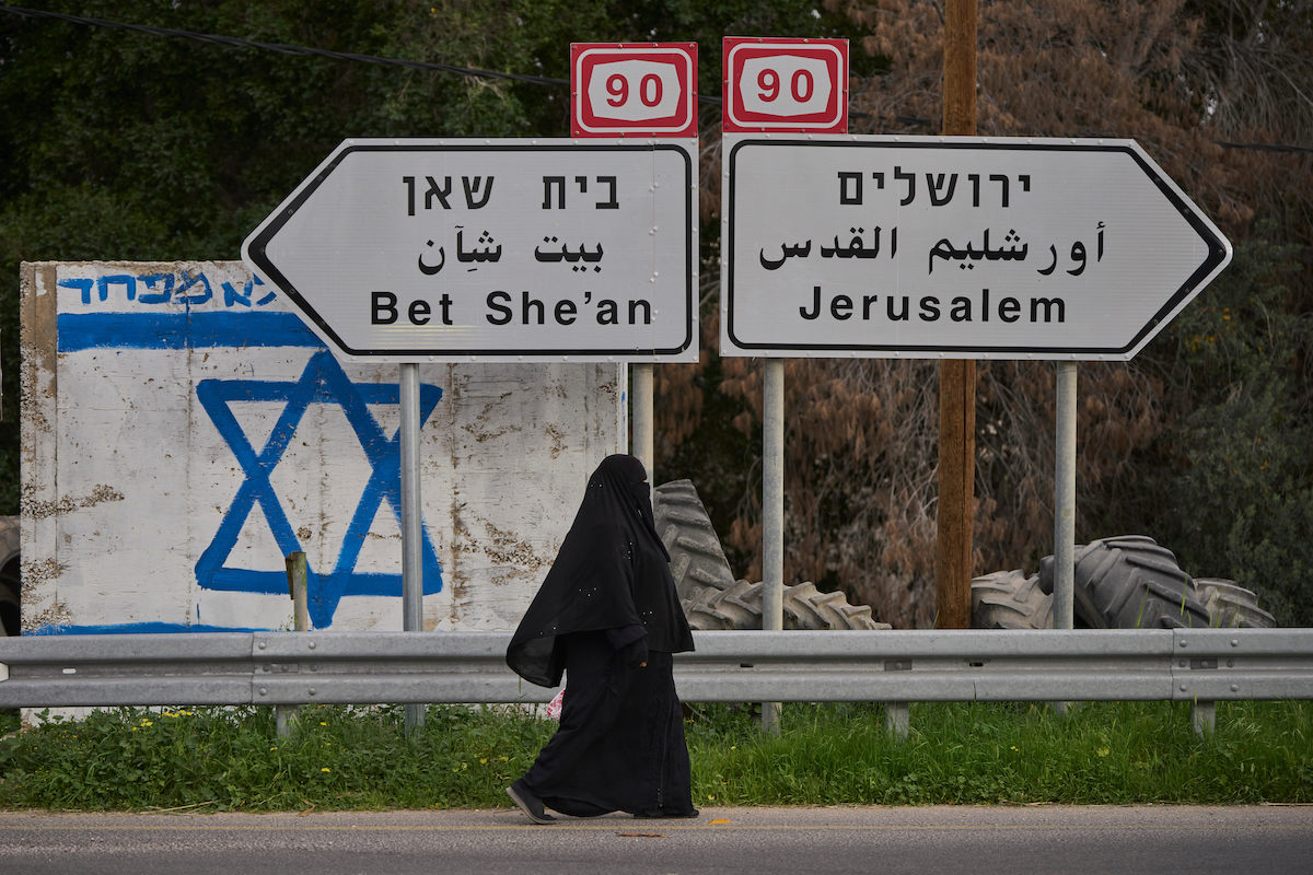 A Palestinian woman walks on the road in the Jordan Valley, West Bank, on Monday. Israel has announced measures to tighten its control of the occupied Palestinian territory. (AP)