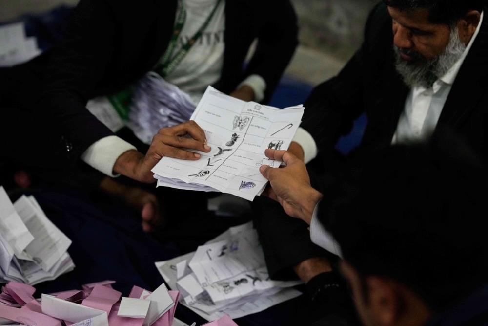 A Bangladeshi polling official hands over ballots shortly after the voting of national parliamentary election ended at a polling station in Dhaka, Bangladesh. (AP)