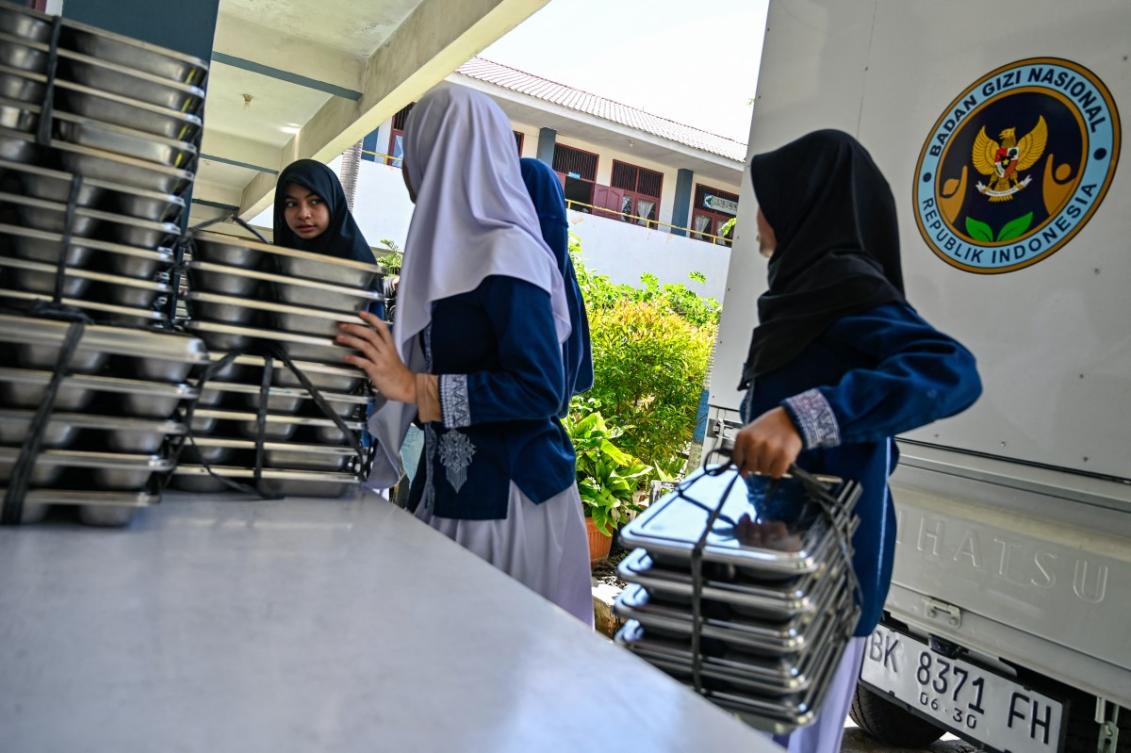 Students collect trays of food supplied by the Indonesian government’s free meal program in Banda Aceh on Oct. 30, 2025. At least 15,000 children across the country have fallen ill as a result of food poisoning since the program was launched. (AFP file photo)