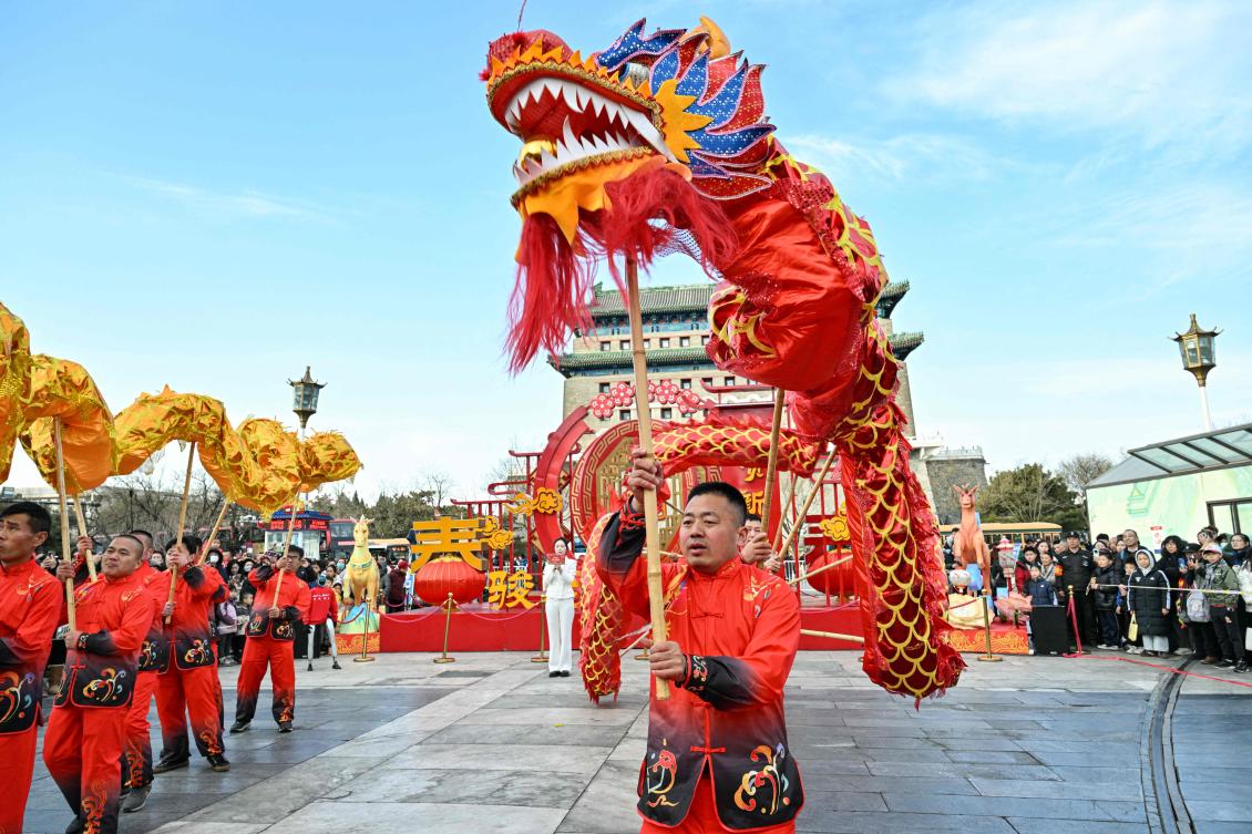 Men participate in a dragon dance on Qianmen Street in Beijing on February 14, 2026, ahead of the Lunar New Year of the Horse. (Photo by ADEK BERRY / AFP)