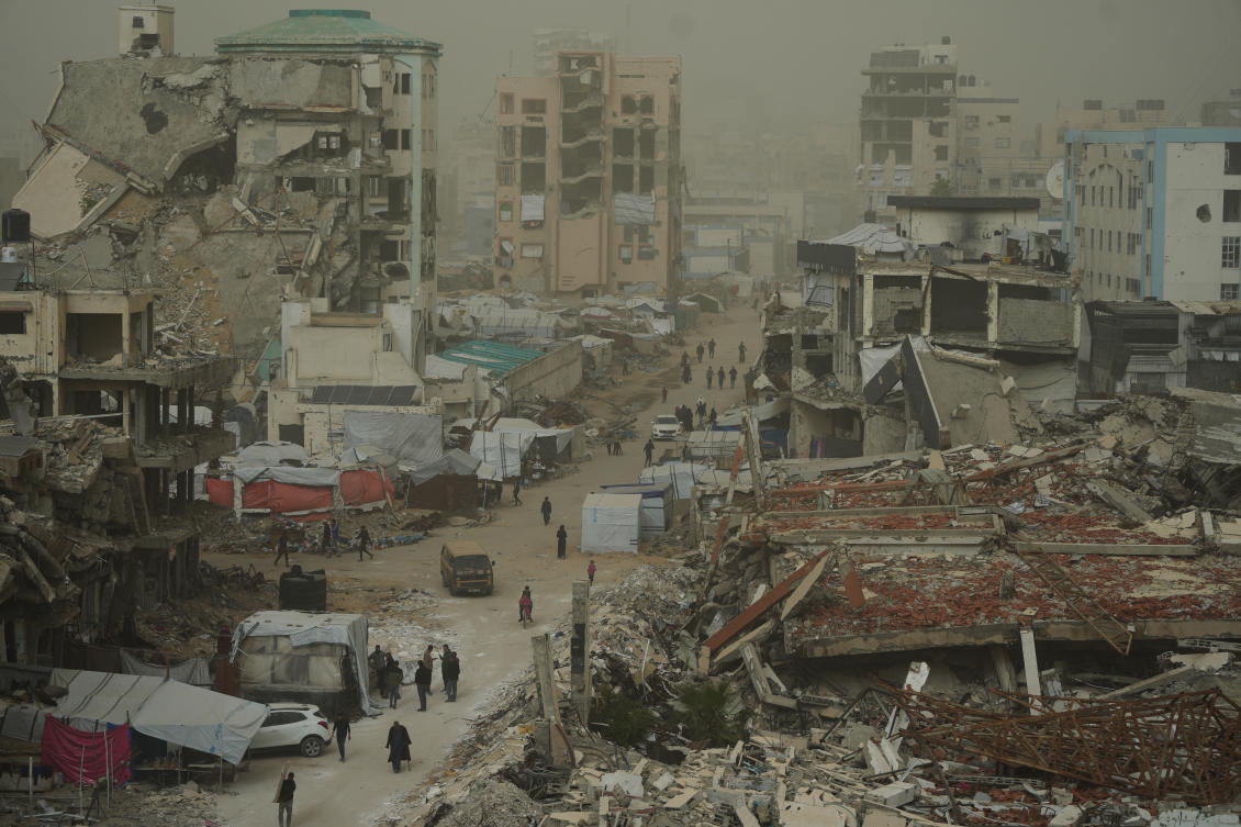 Palestinians walk along a street surrounded by buildings destroyed in Israeli air and ground operations during a dust storm in Gaza City, Saturday, Feb. 14, 2026. (AP)
