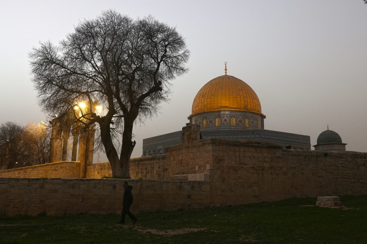 A Palestinian Muslim worshipper walks during a light dust storm past the Dome of the Rock Shrine at the Aqsa mosque compound in the old city of Jerusalem, Feb. 14, 2026. (AFP)