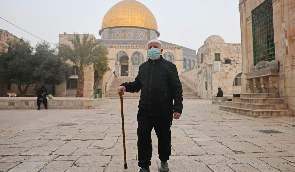 A Palestinian man wears a face mask to protect him from the dust as he walks past the Dome of the Rock mosque in the al-Aqsa Mosque compound, in the old city of Jerusalem on February 14, 2026. (AFP)