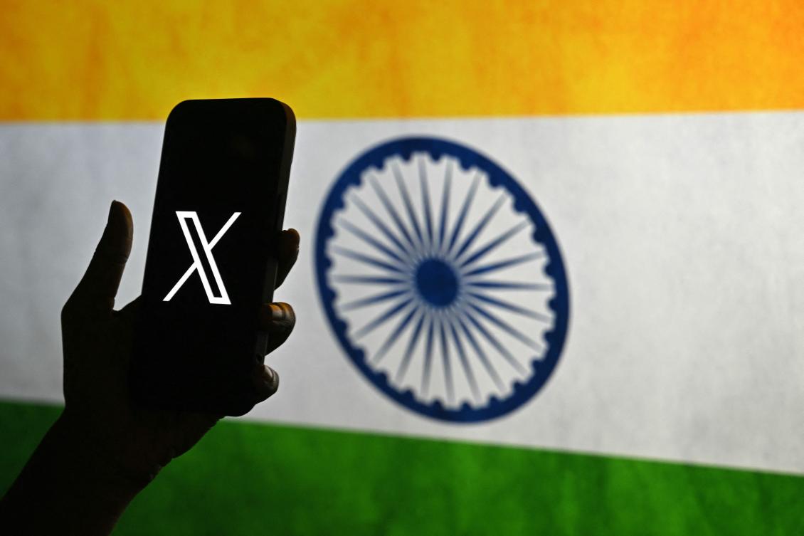 (FILES) This photo illustration shows a person holding a smartphone bearing the logo of X, formerly known as Twitter, in front of the Indian national flag in Bengaluru on January 15, 2026.(AFP)