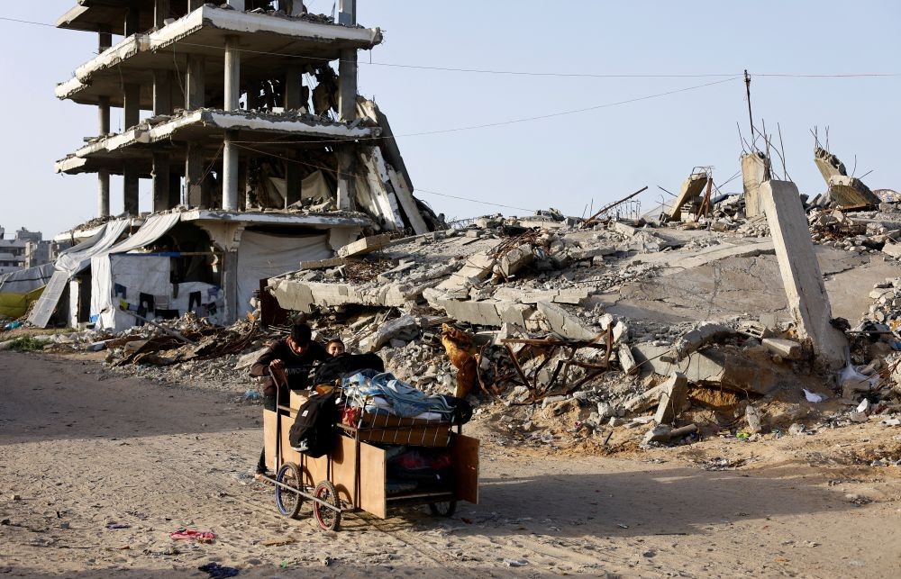 Palestinians push a cart past the rubble of residential buildings destroyed during the two-year Israeli offensive, Gaza City, Feb. 17, 2026. (Reuters)