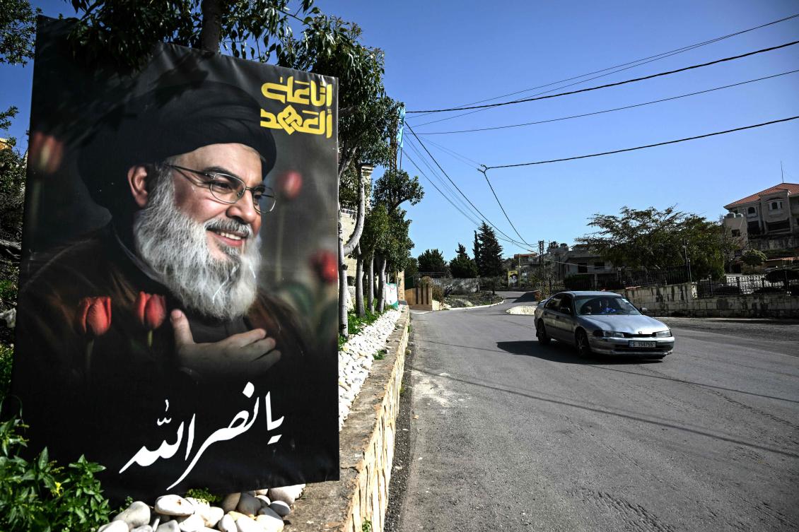 A car drives past a poster of slain Lebanese Hezbollah leader Hassan Nasrallah at the entrance of the southern village of Qannarit. (AFP)
