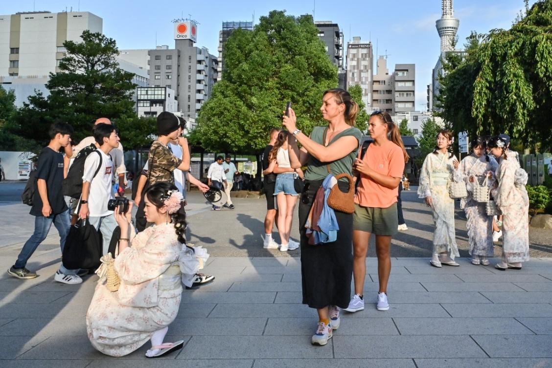 Visitors stop to take photos during a visit to Sensoji Temple in the Asakusa district of central Tokyo on September 16, 2025. (AFP)