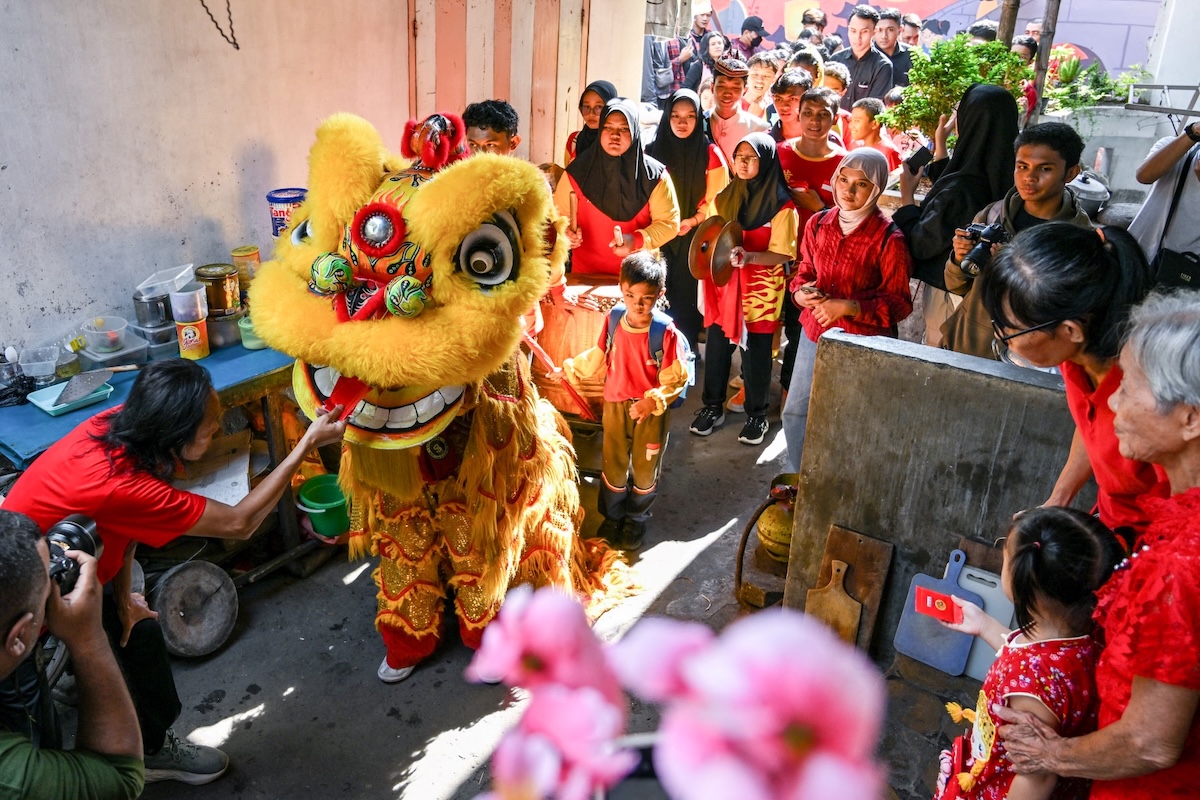 A man gives red envelopes containing money to a lion dancer during Lunar New Year celebrations in Surabaya on Jan. 29, 2025. (AFP)