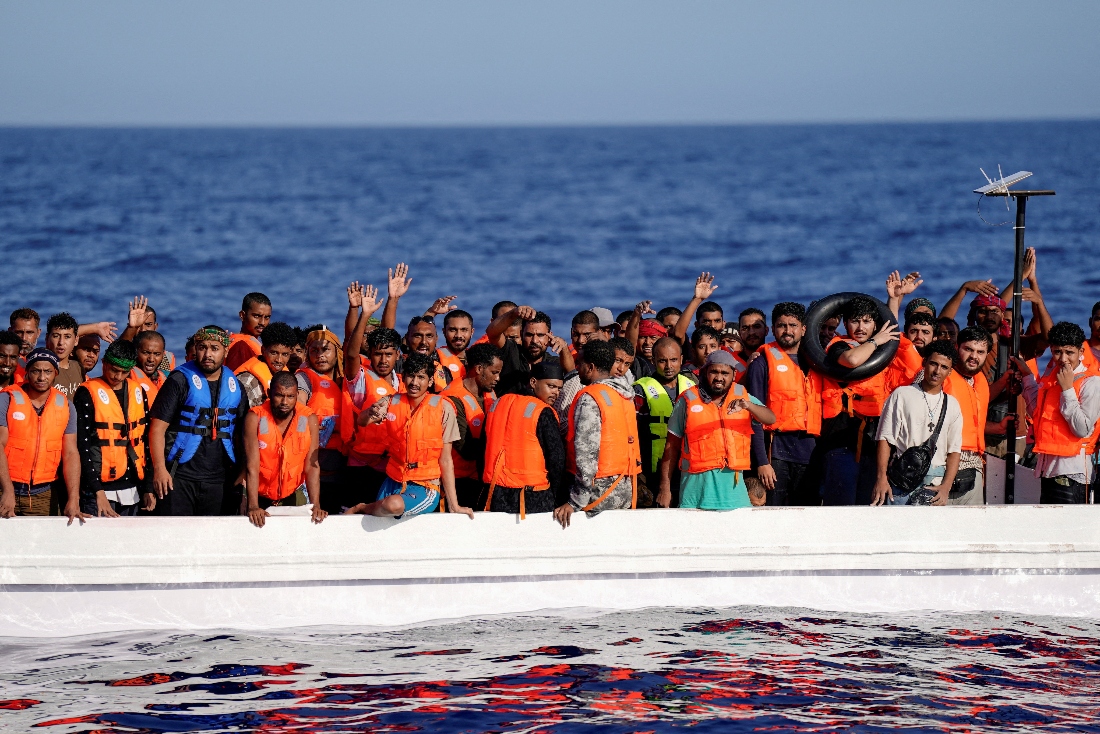 Migrants standing on a fiberglass boat wave at NGO Open Arms rescue boat "Astral" as they assist them in international waters south of Lampedusa, in the Mediterranean Sea. (Reuters)