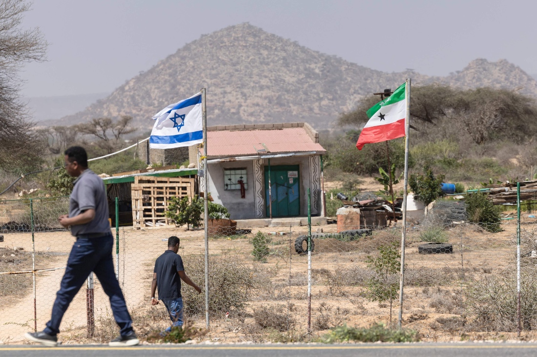 People walk by the flags of Israel and Somaliland flying alongside each other at the entrance to a fruit farm between the capital city of Hargeisa and Port city of Berbera. (AFP)